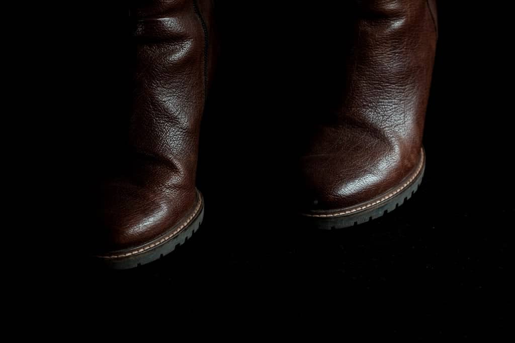 Brown leather boots emerging from a dark background