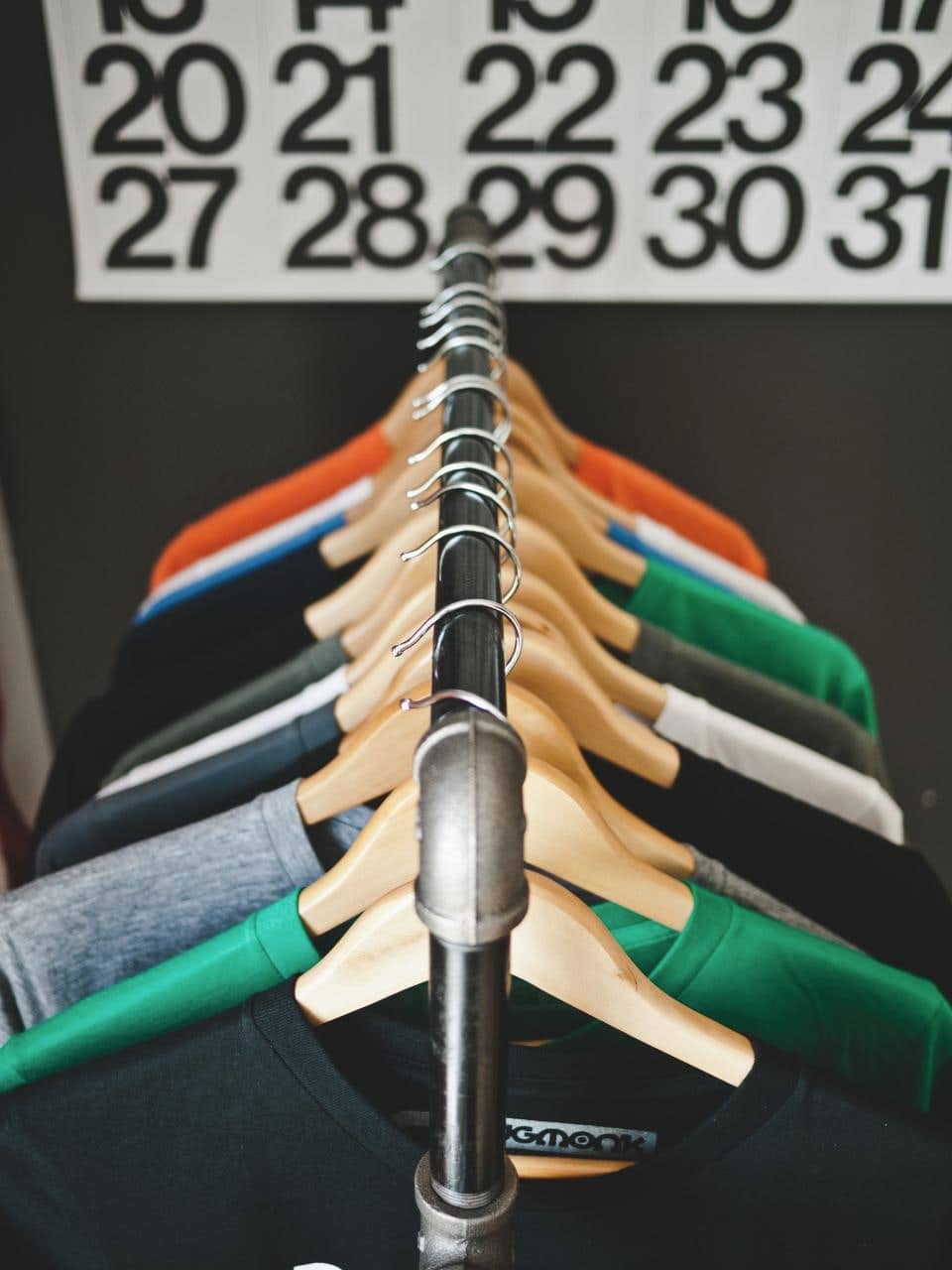 Rail of wooden hangers holding colourful shirts