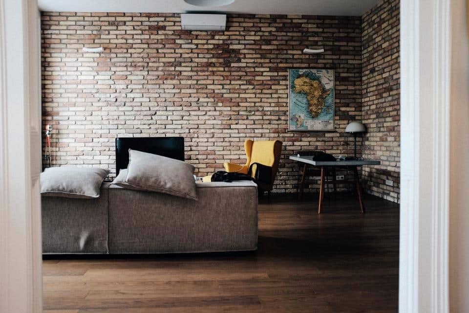 Living room with a grey fabric sofa against a brick wall