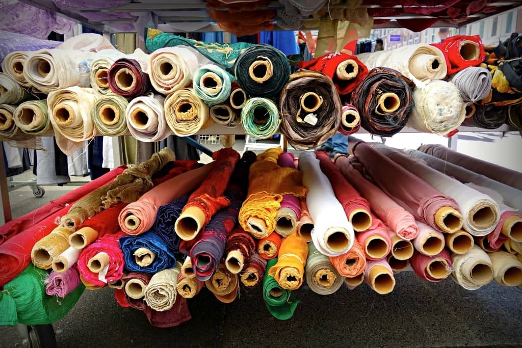 Stacked rolls of colourful fabric at a textile market