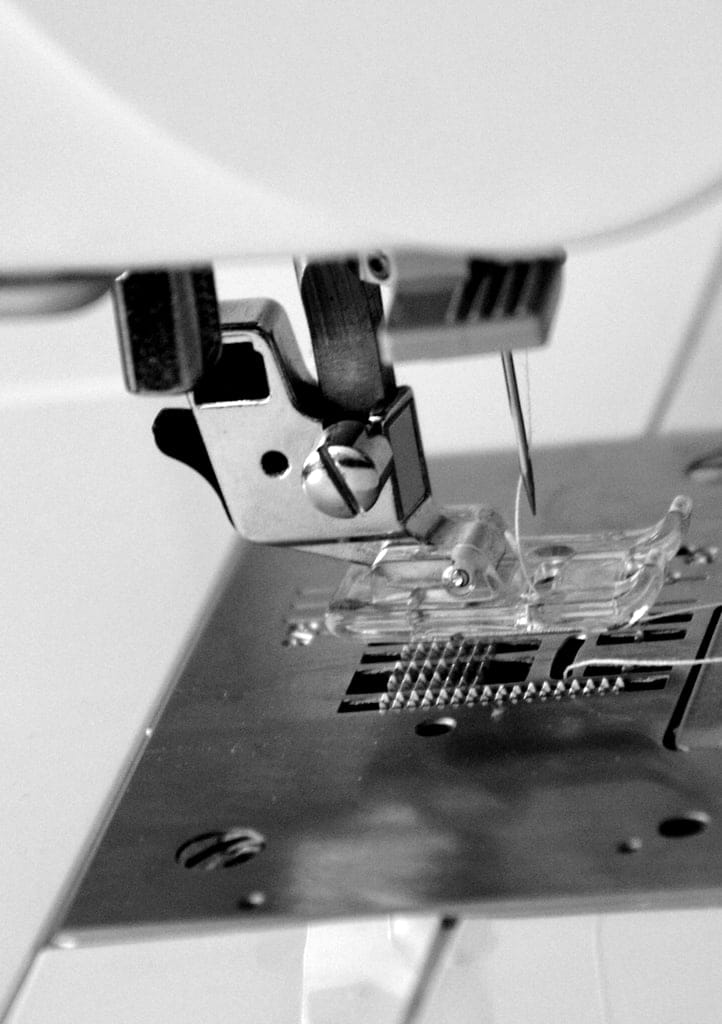 Black and white close-up of an industrial sewing machine presser foot