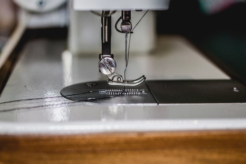 Sewing machine needle and presser foot on a white machine bed