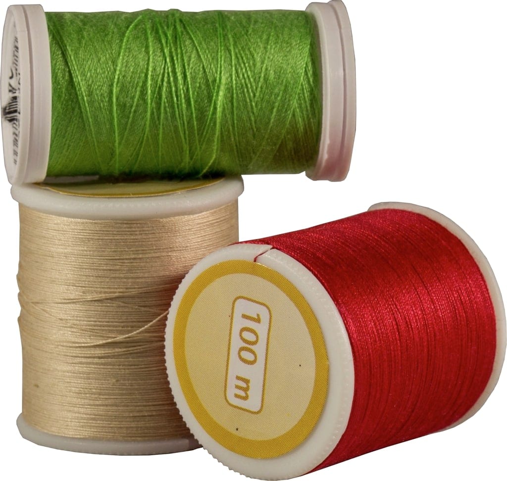 Spools of green, natural beige and red thread stacked together