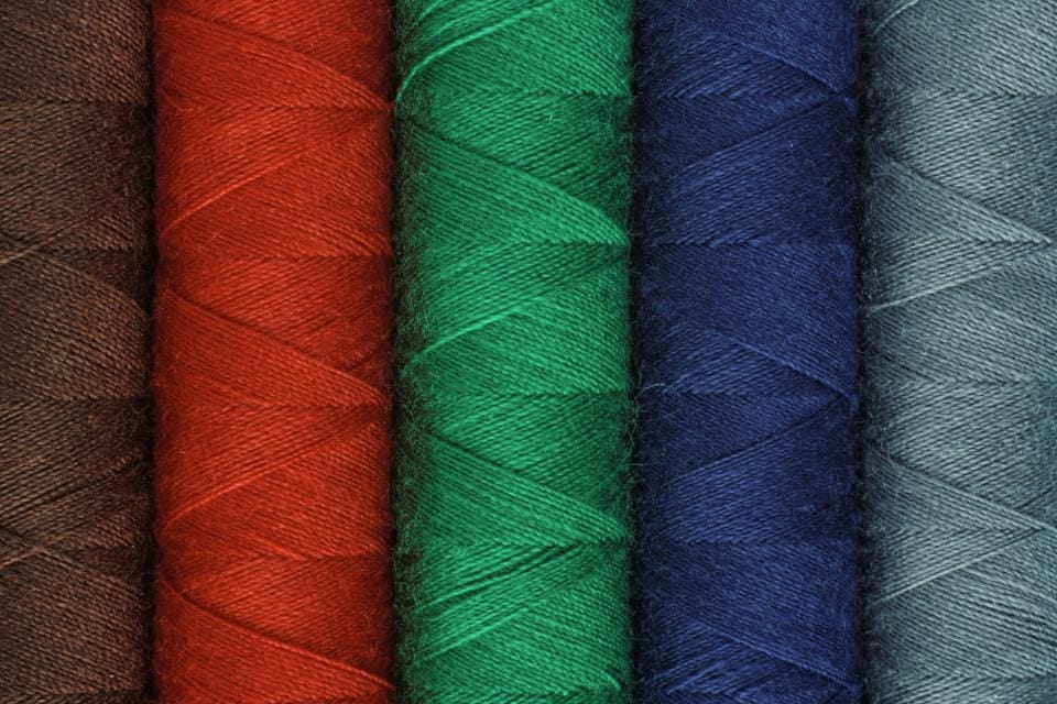 Close-up of tightly wound red, green, navy and teal thread