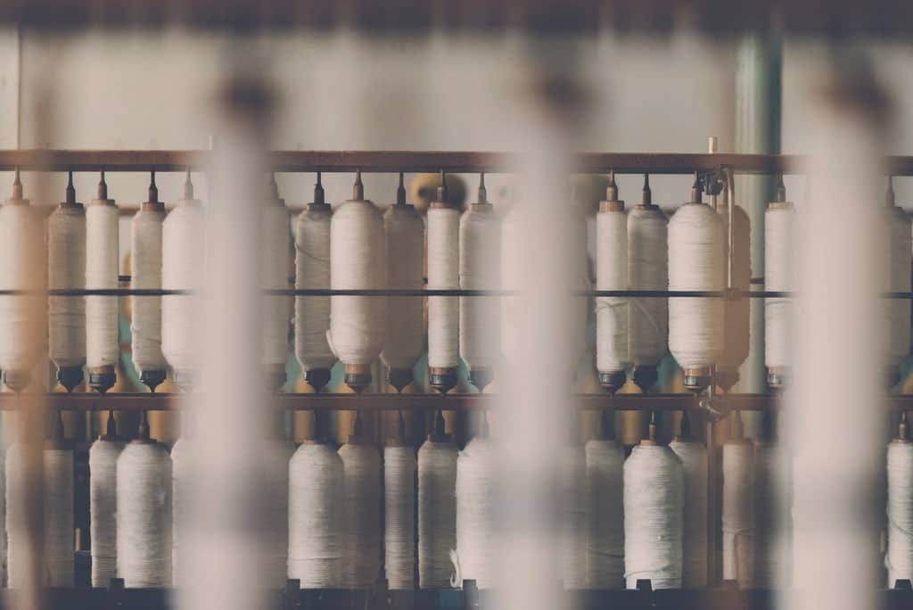 Rows of white yarn bobbins on a spinning frame