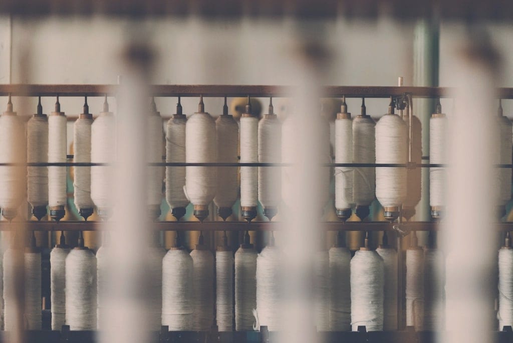 Rows of white yarn bobbins on a spinning frame in a thread mill