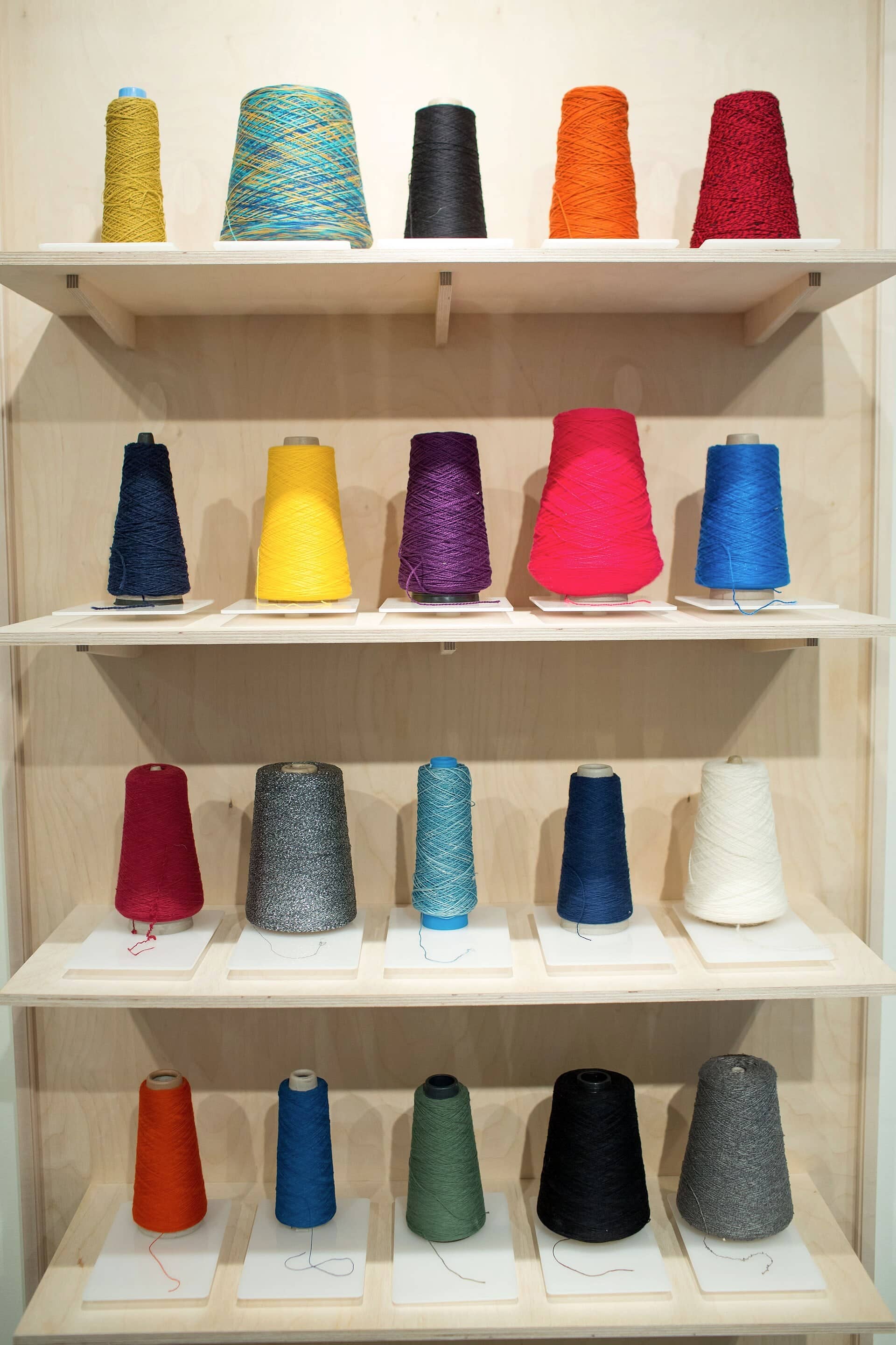 Dyed yarn cones in a spectrum of colours on shelves