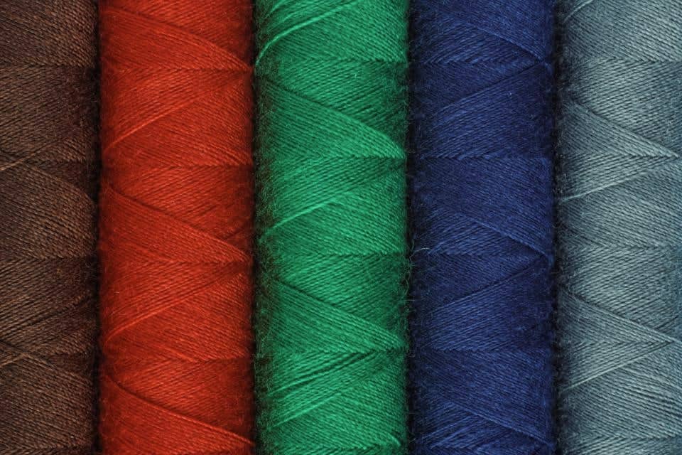 Close-up of tightly wound red, green, navy and teal thread